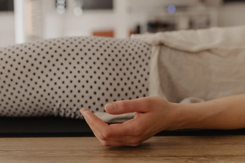 Detaliu din studio — mână pe podeaua de lemn, ambient cald și meditativ